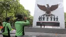 Pengunjung berfoto di depan Monumen Pancasila Sakti, Jakarta Timur, Selasa (1/10/2024). (Liputan6.com/Herman Zakharia)