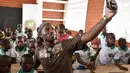 Didier Drogba melakukan foto selfie bersama anak-anak saat membuka sekolah dasar di Onahio, Pokou-Kouamekro, Pantai Gading, (20/1/2018).  Drogba menjadi salah satu sponsor utama untuk sekolah tersebut. (AFP/Sia Kambou)