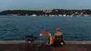 Orang-orang menikmati malam di sebelah pantai Bosphorus ketika jembatan Fatih Sultan Mehmet terlihat di Istanbul (6/7/2020). Ketika diselesaikan pada 1988, jembatan tersebut menjadi jembatan gantung terpanjang ke-5 di dunia; sekarang jembatan tersebut berada pada urutan ke-19. (AFP/Ozan Kose)