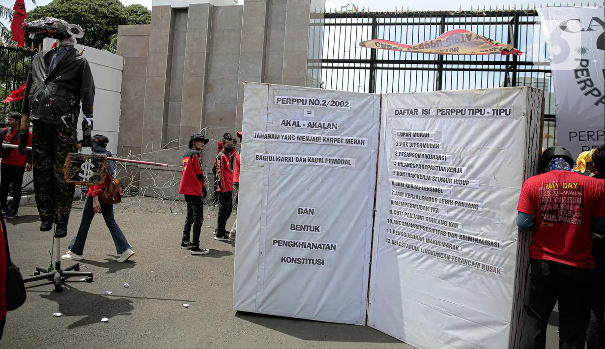 Puluhan elemen buruh menggeruduk gedung DPR RI, Jakarta, Selasa (10/1/2023). Massa juga menggantung banner besar bertuliskan "cabut Perppu No 2 Tahun 2022" di pintu utama Gedung DPR. (Liputan6.com/Faizal Fanani)