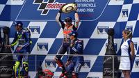 Pembalap Repsol Honda, Marc Marquez (tengah) mengangkat trofi usai keluar sebagai juara MotoGP Australia di Phillip Island (22/10). Dalam MotoGP Australia ini tempat kedua diisi Rossi dan ketiga menjadi milik Vinales. (AFP Photo/Paul Crock)