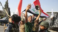 Warga berswafoto dengan polisi Federal Irak  saat merayakan keberhasilan menyingkirkan militan ISIS dari Kota Tua Mosul, Minggu (9/7). Pertempuran Mosul telah meninggalkan sebagian besar kota terbesar kedua Irak itu dalam reruntuhan. (AHMAD AL-RUBAYE/AFP)