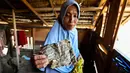 Warga berharap pembangunan dapat dipercepat agar mereka bisa segera pindah dari tenda darurat dan menjalani sisa Ramadan serta merayakan Idul Fitri di tempat yang lebih layak dan aman. Tampak dalam foto, Rauzah, seorang ibu empat anak yang selamat dari banjir, memegang halaman-halaman kotor dari buku yang digunakan anak-anak untuk belajar membaca Al-Quran, di rumahnya yang rusak di Meurah Dua, Kabupaten Pidie Jaya, Provinsi Aceh, pada 21 Februari 2026, setelah banjir dan tanah longsor dahsyat melanda Sumatra, akhir November 2025 lalu. (CHAIDEER MAHYUDDIN/AFP)