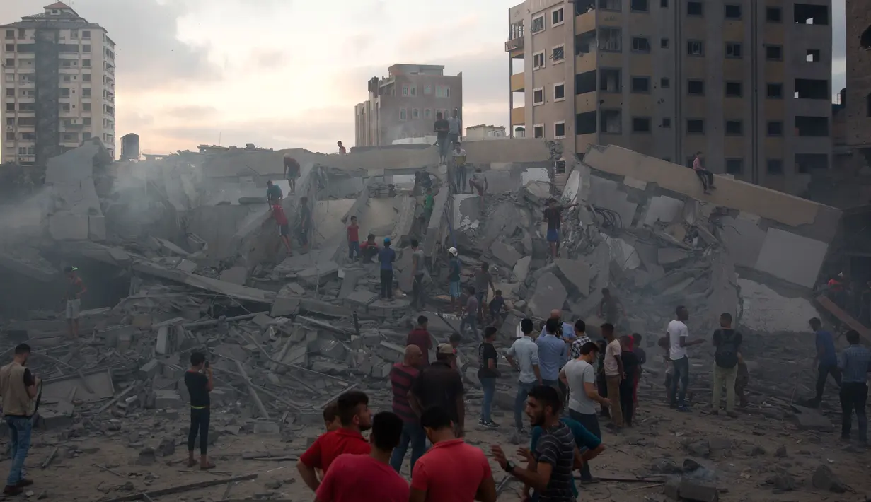 Warga melihat puing-puing bangunan yang hancur akibat serangan udara Israel di Kota Gaza, Palestina, (9/8). Tentara Israel kembali membombardir Gaza sebagai aksi balasan terhadap serangan militan Hamas. (AP Photo/Khalil Hamra)
