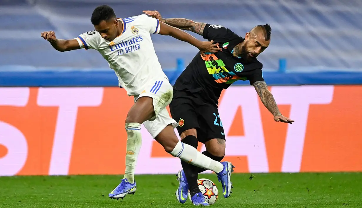 Pemain Real Madrid Rodrygo (kiri) berebut bola dengan pemain Inter Milan Arturo Vidal pada pertandingan sepak bola Grup D Liga Champions di Stadion Santiago Bernabeu, Madrid, Spanyol, 7 Desember 2021. Real Madrid menang 2-0. (PIERRE-PHILIPPE MARCOU/AFP)