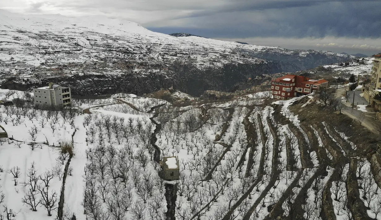 Kota Bcharre yang tertutup salju, menghadap ke lembah Qadisha di gunung Lebanon, di utara ibu kota Beirut (22/2/2022).(AFP/Ibrahim Calhoub)