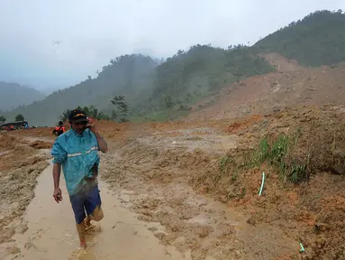 Warga melintas di atas perkampungan yang tertimbun longsor di Dusun Cimapag, Desa Sirnaresmi, Kecamatan Cisolok, Sukabumi, Selasa (1/1). BNPB mencatat, sebanyak 41 orang diduga masih tertimbun longsoran. (merdeka.com/Arie Basuki)