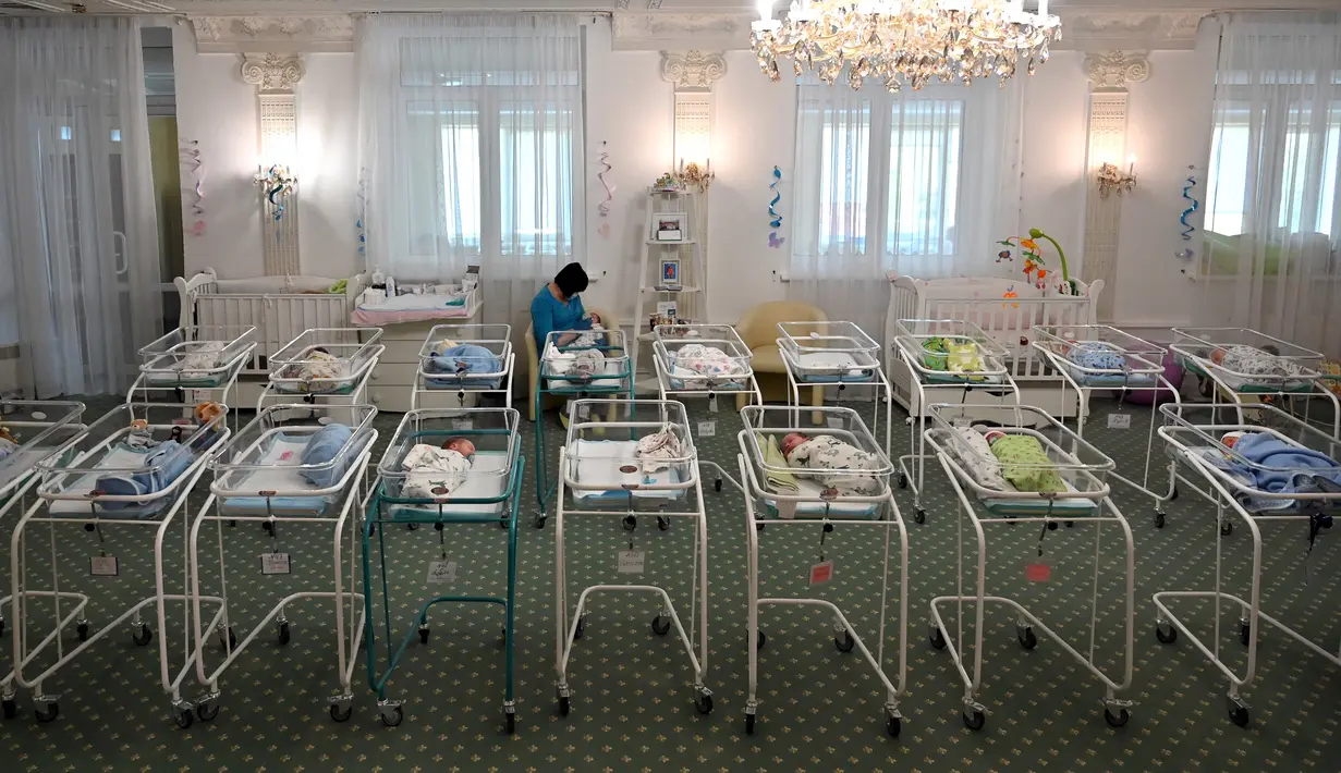 Perawat merawat bayi yang baru lahir dari skema ibu pengganti (surrogate mother) di Hotel Venice, Kiev, Ukraina, 15 Mei 2020. Sekitar 100 bayi yang lahir dari skema ibu pengganti telantar di Ukraina. (Sergei SUPINSKY/AFP)