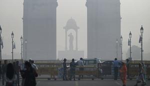 Pejalan kaki berjalan di sepanjang jalan dekat Gerbang India di tengah kabut asap tebal di New Delhi, Kamis (3/11/2022). Setiap musim dingin, udara dingin beserta asap dari petani yang membakar jerami dan emisi kendaraan juga sumber-sumber lainnya bercampur menciptakan kabut asap mematikan. (Money SHARMA / AFP)