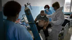 Spesialis penyakit Infeksi Bulgaria Dr Maria Bogoeva (kiri) mengamati rekan kerja memeriksa pasien di unit Covid-19 di sebuah rumah sakit kecil di Bulgaria pada 20 Januari 2021. Perempuan berusia 82 tahun itu siap untuk pensiun dari jabatannya ketika pandemi virus corona melanda. (Dimitar DILKOFF/AF