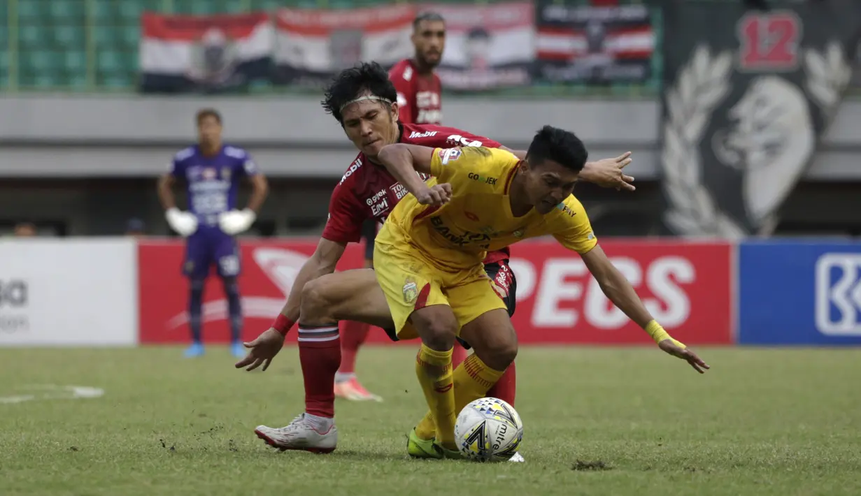 Gelandang Bhayangkara FC, Dendy Sulistiawan, berebut bola dengan bek Bali United, Michael Orah, pada laga Shopee Liga 1 di Stadion Patriot Chandrabhaga, Bekasi, Jumat (13/9). Bhayangkara bermain imbang 0-0 atas Bali United. (Bola.com/Yoppy Renato)