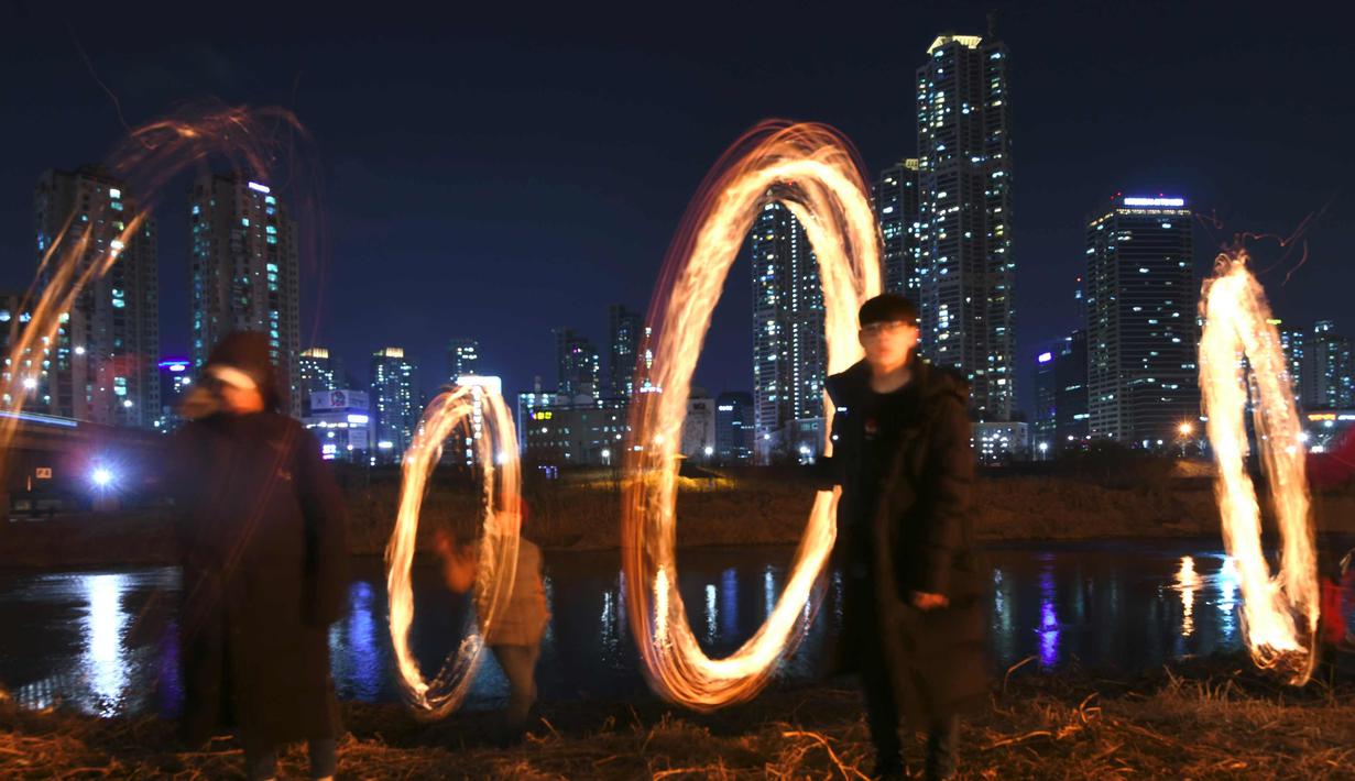 Peserta membuat lingkaran api jelang perayaan "Jeongwol Daeboreum" (Bulan Purnama) di Seoul, Korea Selatan (1/3). Permainan ini dipercaya dapat menyuburkan tanah dan menyingkirkannya hama sehingga memastikan hasil panen melimpah. (AFP Photo/Jung Yeon-je)