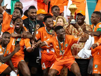 Presiden Pantai Gading Alassane Ouattara (tengah) mengangkat trofi Piala Afrika di podium setelah Les Elephants memenangkan pertandingan sepak bola final Piala Afrika (CAN) melawan Nigeria di Stadion Olimpiade Alassane Ouattara, Ebimpe, Abidjan pada 11 Februari 2024. (FRANCK FIFE/AFP)