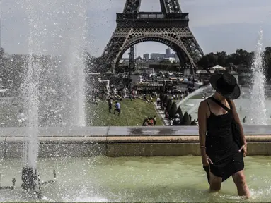 Seorang wanita mendinginkan kakinya di sebuah kolam di Trocadero Fountains dekat Menara Eiffel, Paris (22/7/2019). Warga Paris bersiap menghadapi suhu terpanas pada minggu ini ketika gelombang panas akan melanda ke Eropa utara. (AFP Photo/Alain Jocard)