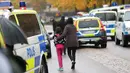 Seorang murid dan orangtuanya meninggalkan sekolah Kronan di Trollhattan, Swedia barat, Kamis (22/10). Pria bertopeng dan bersenjatakan pedang menyerang sekolah tersebut dan menewaskan seorang murid dan guru. (REUTERS/Bjorn Larsson Rosvall/TT News Agency)