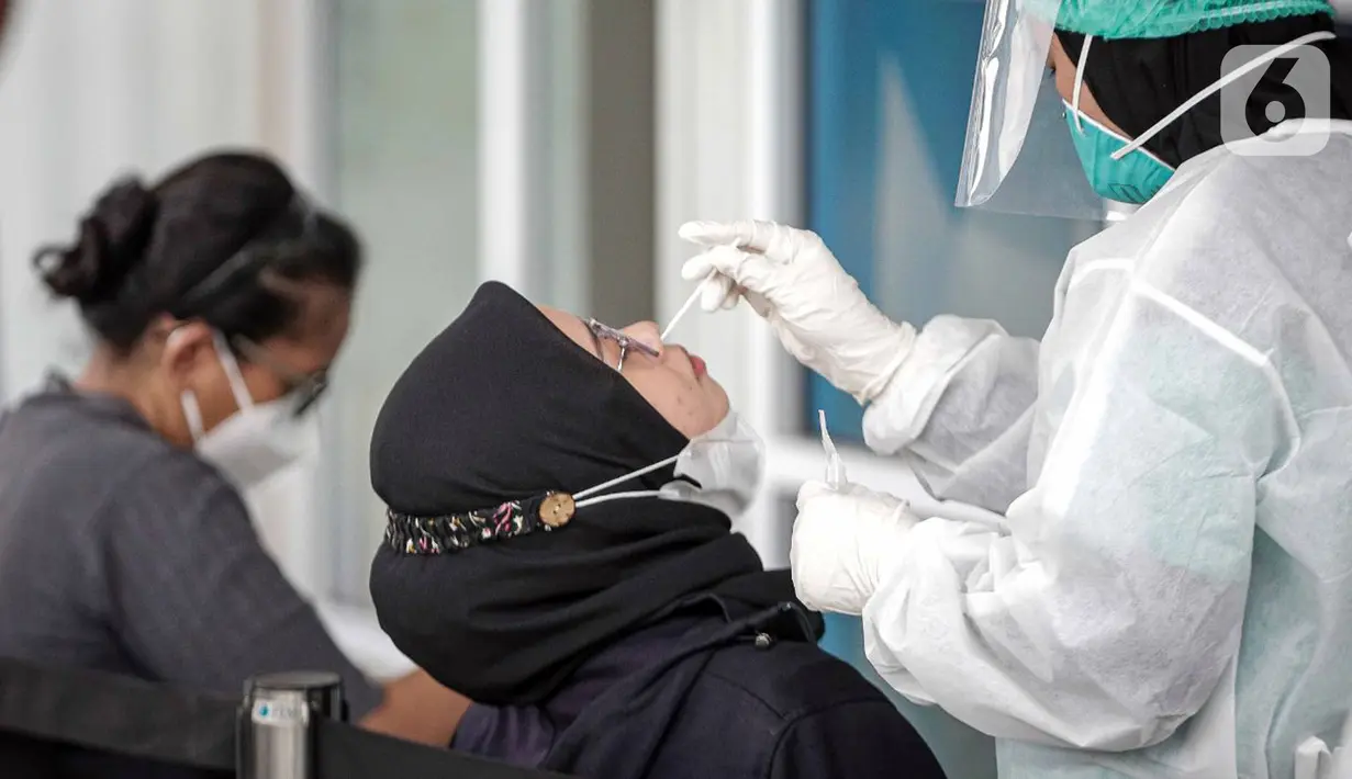 Petugas melakukan tes usap PCR kepada warga di Laboratorium Genomik Solidaritas Indonesia (GSI), Kamis (3/2/2022). Lonjakan kasus COVID-19 kembali terjadi diduga akibat varian Omicron yang mudah menular. (Liputan6.com/Faizal Fanani)