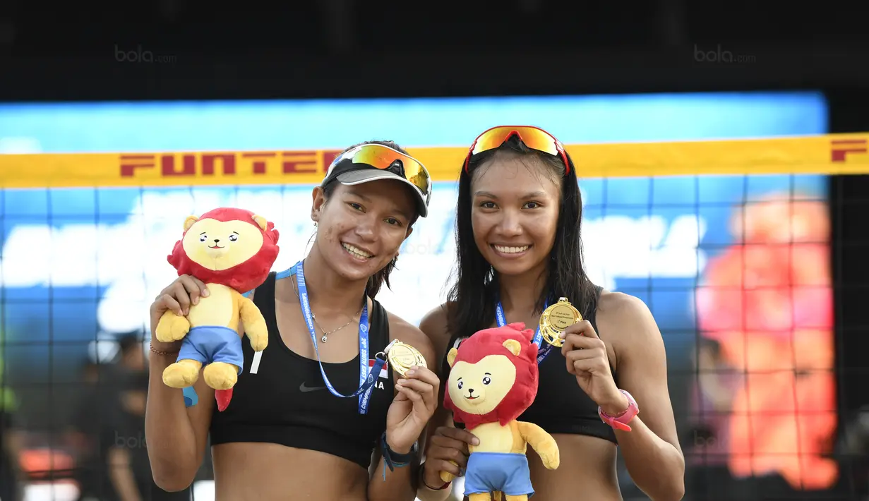 Pevoli Pantai Indonesia, Juliana/Utami memamerkan Medali Juara usai mengalahkan pevoli Thailand Numwong/Hongpak pada Kejuaraan Bola Voli Pantai ke-29 yang diadakan di Singapura, Rabu (30/9/2017) (Bola.com/Wong Foo Lam)