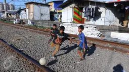 Anak-anak bermain bola di jalur kereta api di permukiman kampung bandan, Jakarta, Jumat (15/7). Badan Direksi Bank Dunia dan Bank Investasi Infrastruktur Asia (AIIB) menyetujui pemberian pendanaan sebesar US$ 433 juta. (Liputan6.com/Angga Yuniar)