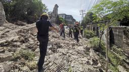 Penyelamat berjalan melewati puing-puing bangunan yang runtuh setelah gempa kuat melanda Vigan, Provinsi Ilocos Sur, Filipina, 27 Juli 2022. Sebanyak empat orang dilaporkan tewas dan puluhan lainnya terluka dalam akibat gempa. (Bureau of Fire Protection via AP)