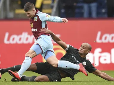Aksi bek Manchester City, Vincent Kompany (kanan) menghalau bola dari kaki pemain Burnley, Berg Gudmundsson (kiri) pada lanjutan Premier League di Turf Moor  Stadium, Burnley, (3/2/2018). Burnley tahan Manchester City 1-1. (AFP/Oli Scarff)