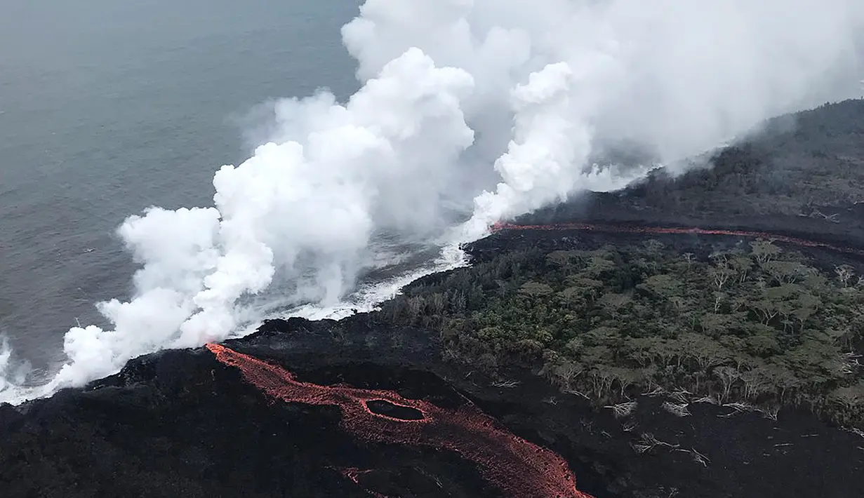 Lava pijar Gunung Kilauea saat mengalir ke laut di dua lokasi dekat Pahoa, Hawaii, Amerika Serikat, Senin (21/5). Lava pijar mengalir ke laut dan memicu reaksi kimia yang menciptakan awan raksasa asam dan kaca halus. (Survei Geologi AS via AP)