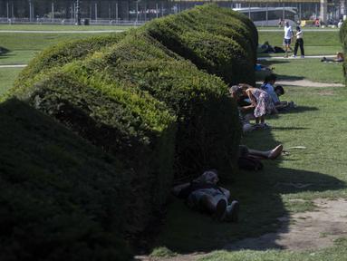 Para pejalan kaki berbaring di bawah naungan Jardin du Carrousel di Paris, Prancis pada 11 Agustus 2025, di tengah gelombang panas yang melanda Eropa. (Martin LELIEVRE/AFP)