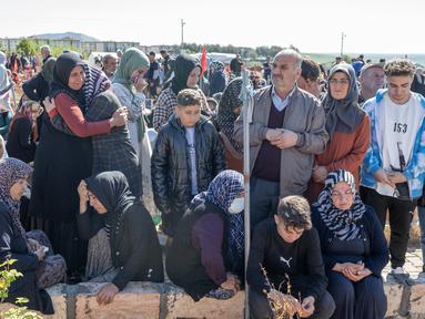Orang-orang meratapi para korban yang dilanda gempa pada hari pertama Idul Fitri di pemakaman, di Adiyaman, Turki pada 21 April 2023. (AFP/BULENT KILIC)
