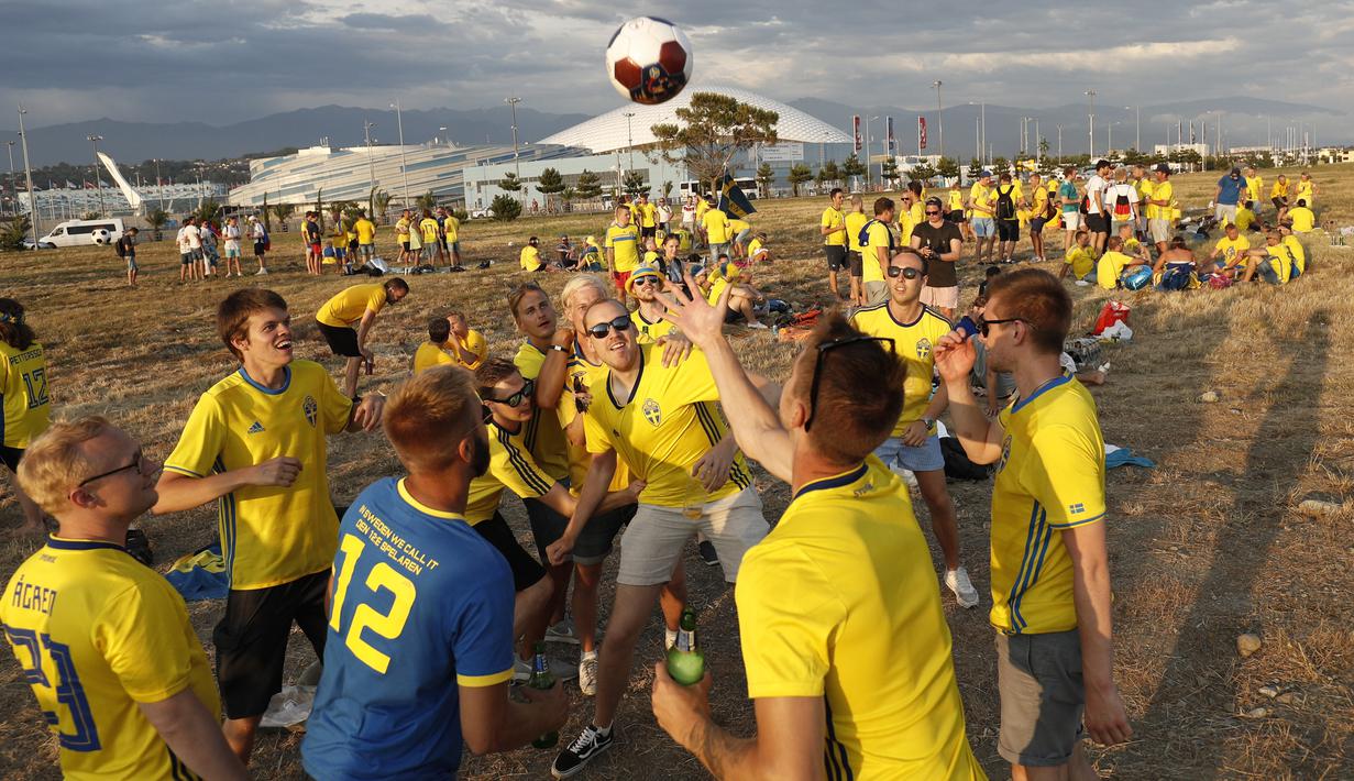 Sejumlah suporter Swedia bergembira bermain bola di sekitar Pantai Sochi, Jumat (22/6/2018). Para suporter bersiap untuk menyaksikan laga Piala Dunia 2018 antara Swedia melawan Jerman. (AFP/Adrian Dennis)