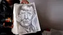 Farhad Nouri memperlihatkan lukisan Kanselir Jerman Angela Merkel yang dibuatnya, di kamarnya di dekat Belgrade, Serbia, 13 Maret 2017. Bocah Afganistan berusia 10 tahun ini dikenal dengan julukan Little Picasso karena bakat seninya. (AP/Darko Vojinovic)