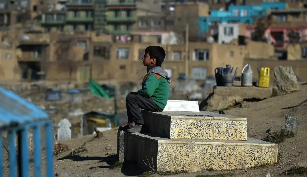 Afghan Zilgai (9), bocah penjual air ketika tengah menunggu pembeli di pemakaman Kart-e-Sakhi, Kabul, 20 Februari 2016. Anak sulung dari 8 bersaudara itu menjual air dari fajar hingga senja kepada para peziarah. (AFP PHOTO/Wakil KOHSAR)