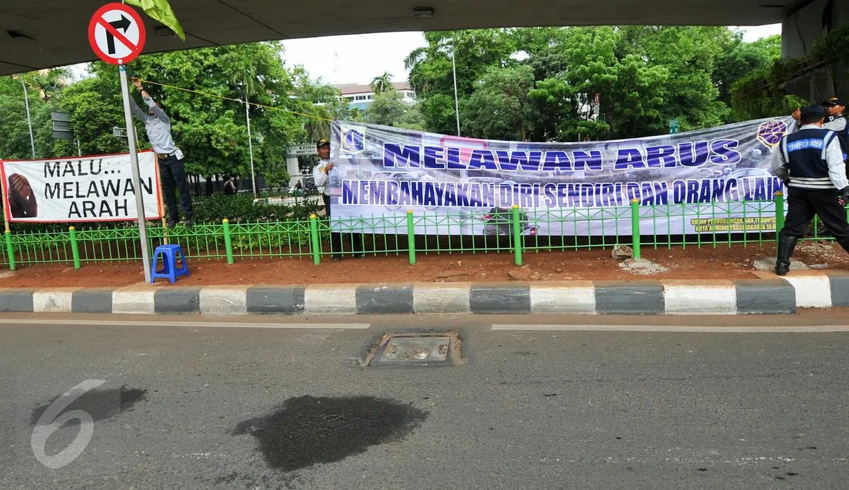 Petugas Dishub Jakarta memasang spanduk besar larangan melawan arus di putaran bawah jembatan layang Kalibata atau tepatnya setelah perlintasan kereta api Kalibata, Jakarta, Rabu (16/12/2015). (Liputan6.com/Yoppy Renato)