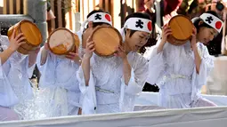 Sejumlah wanita penganut agama Shinto melakukan mandi air dingin di Kuil Kanda, Tokyo, Jepang (13/1). Upacara ini diawali dengan pemberkatan oleh pendeta. Acara dilanjutkan dengan lari pagi mengelilingi kuil. (AFP Photo/Toshifumi Kitamura)
