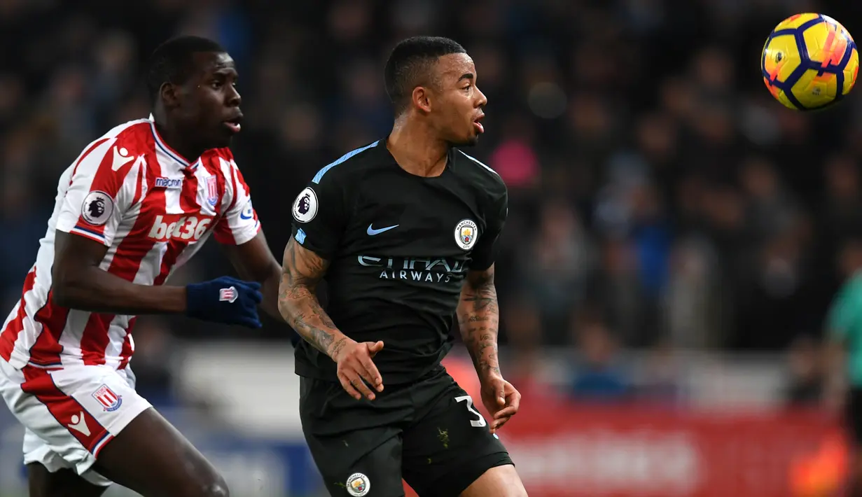 Bek Stoke City Kurt Zouma berebut bola dengan striker Manchester City, Gabriel Jesus pada pertandingan pekan ke-30 Premier League di bet365 Stadium, Selasa (13/3). Manchester City sukses menaklukkan Stoke City dengan skor 2-0. (PAUL ELLIS/AFP)