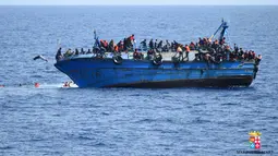 Sebuah perahu yang menampung 500 lebih imigran asal Timur Tengah tersebut tampak miring sebelum akhirnya terbalik dan tenggelam di lepas pantai Libya, Rabu (25/5). Kandasnya perahu diduga akibat kelebihan muatan. (STR/AFP MARINA MILITARE/AFP)
