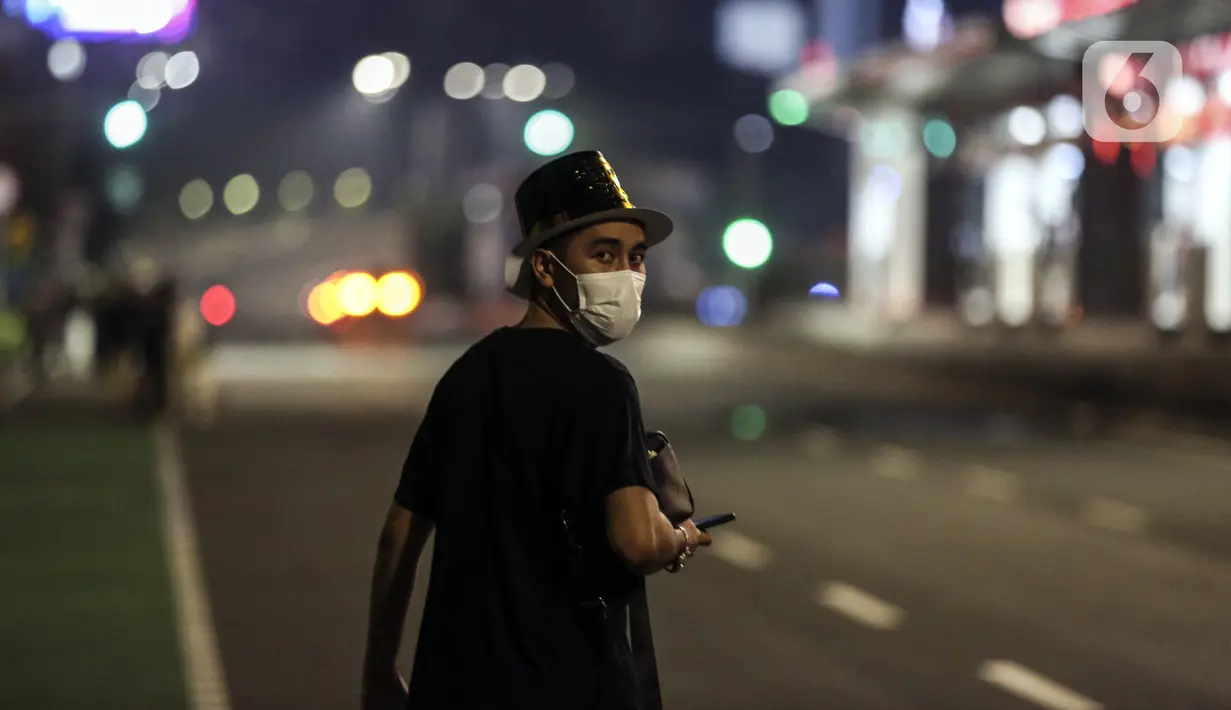 Warga jalan pergi usai dibubarkan petugas saat perayaan malam Tahun Baru di Jakarta, Jumat (31/12/2021). Polda Metro Jaya melakukan pengendalian mobilitas Crowd Free Night (malam bebas keramaian) dengan membubarkan warga yang nekat keluar rumah dan tidak mematuhi aturan. (Liputan6.com/Johan Tallo)