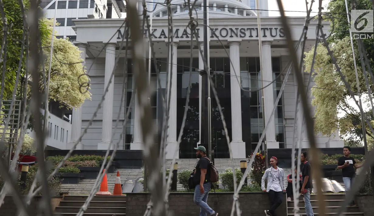 Pewarta berjalan melintasi halaman depan Gedung Mahkamah Konstitusi, Jakarta, Kamis (13/6/2019). Mahkamah Konstitusi akan menggelar sidang Perselisihan Hasil Pemilihan Presiden/Wakil Presiden Pemilu 2019 pada, Jumat (14/6). (Liputan6.com/Helmi Fithriansyah)