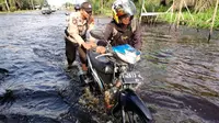 Personel Polres Pelalawan mendorong kendaraan mogok karena nekat melewati banjir di Jalan Lintas Timur Sumatra. (Liputan6.com/M Syukur)