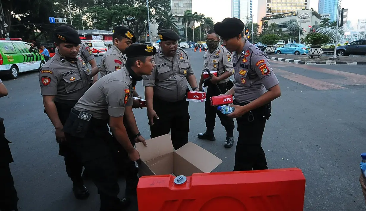 Aparat kepolisian yang melakukan penjagaan mendapatkan makanan berbuka puasa dari relawan TKN Jokowi-Ma'ruf Amin di kawasan Bundaran HI, Jakarta, Jumat (24/5/2019). Kegiatan ini sebagai bentuk kepedulian untuk aparat yang telah menjaga keamanan di Jakarta. (Liputan6.com/Angga Yuniar)