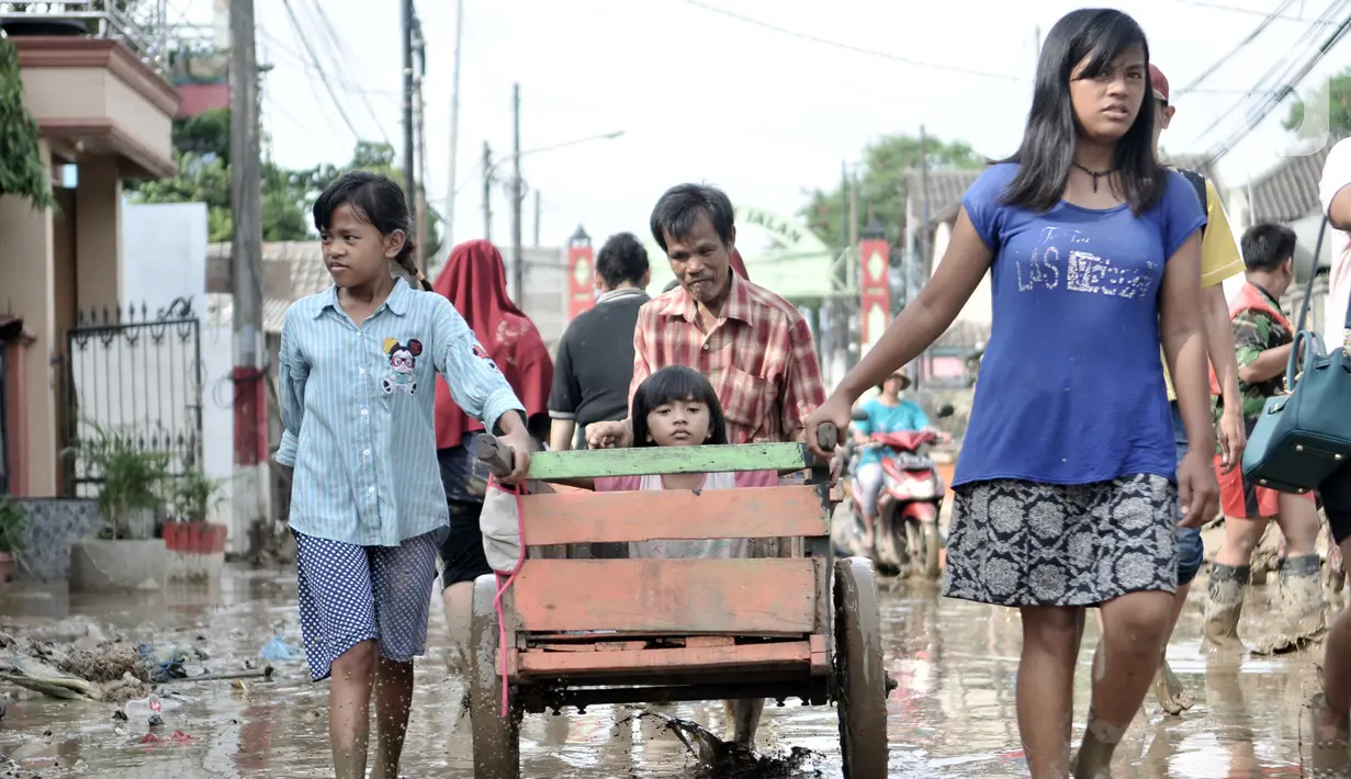 Seorang anak didorong menggunakan gerobak usai banjir menerjang Perumahan Pondok Gede Permai, Jatiasih, Bekasi, Jawa Barat, Kamis (2/1/2020). Terjangan banjir setinggi lima meter tersebut menyisakan lumpur dan sampah yang memenuhi seluruh kompleks perumahan. (merdeka.com/Iqbal Nugroho)