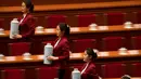 Wanita-wanita cantik membawa termos air panas untuk teh jelang pembukaan Kongres Rakyat Nasional (NPC) di Aula Besar Rakyat, Beijing, Senin (19/3). Selain cantik, mereka juga tampil kompak dalam menuangkan teh untuk peserta kongres. (AP/Mark Schiefelbein)