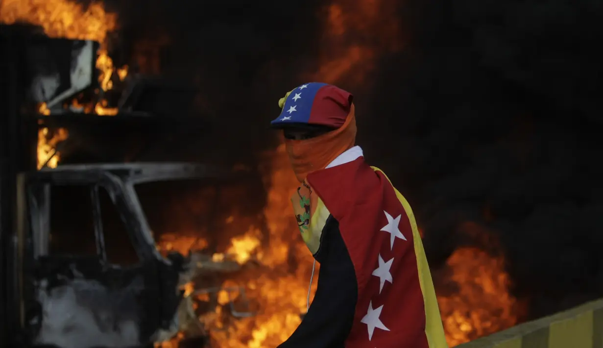 Demonstran anti-pemerintah di Venezuela menutupi wajahnya saat menggelar aksi di Caracas, Venezuela, Sabtu (26/5). Demonstrasi terus terjadi seiring krisis bahan kebutuhan pokok di penjuru negeri. (AP Photo)  