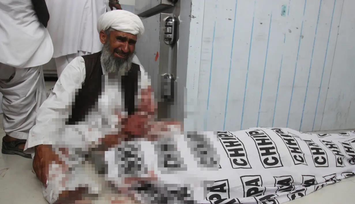 Seorang pria menangis di dekat anggota keluarganya yang tewas akibat aksi bom bunuh diri di Quetta, Pakistan, (13/7). ISIS telah menyatakan bertanggung jawab atas aksi serangan bom bunuh diri tersebut. (AP Photo/Arshad Butt)