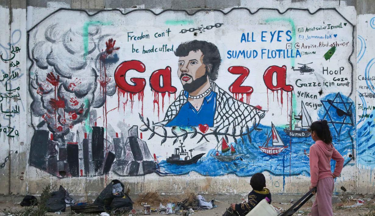 Anak-anak Palestina melihat mural yang menggambarkan pencegatan kapal-kapal yang berpartisipasi dalam Armada Sumud Global, sebuah misi bantuan kemanusiaan yang dipimpin sipil ke Gaza melalui laut, di Nuseirat, Jalur Gaza Tengah pada 19 Mei 2026. (Eyad Baba/AFP)