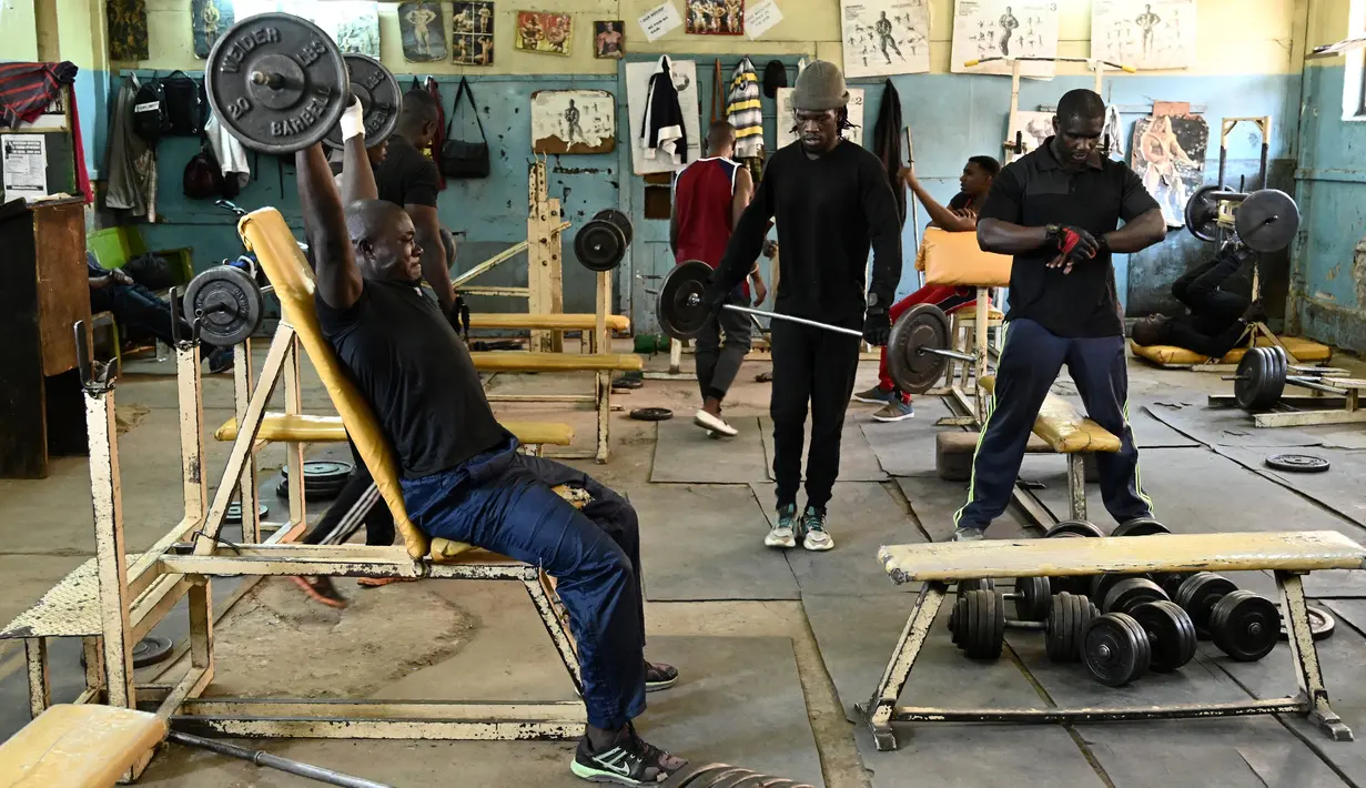 Sejumlah binaragawan mengangkat beban saat berolahraga di gym Kaloleni, di Nairobi, Kenya (9/1). (AFP Photo/Simon Maina)