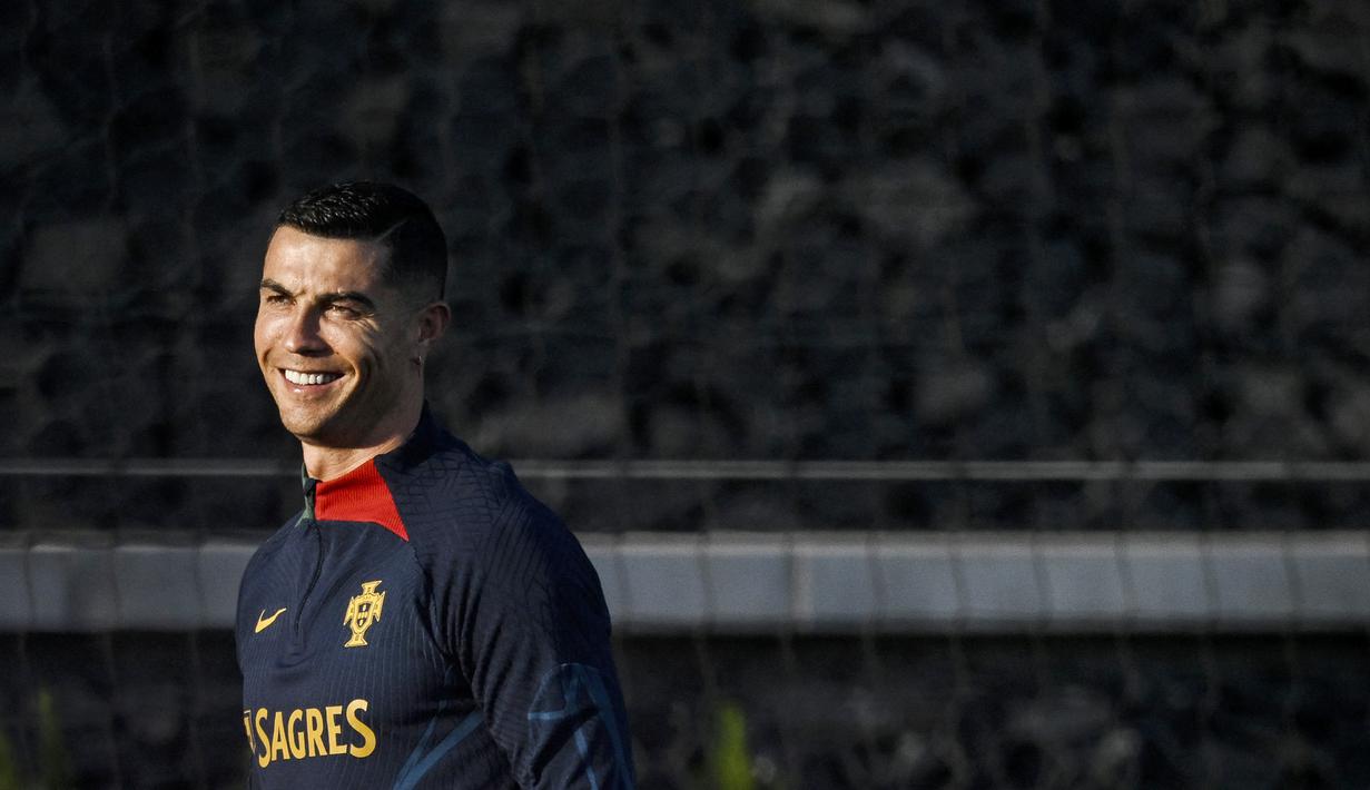 Pemain Portugal, Cristiano Ronaldo, tersenyum saat mengikuti sesi latihan jelang menghadapi laga Kualifikasi Euro 2024 di Lisbon, (20/3/2023). (AFP/Patricia De Melo Moreira)
