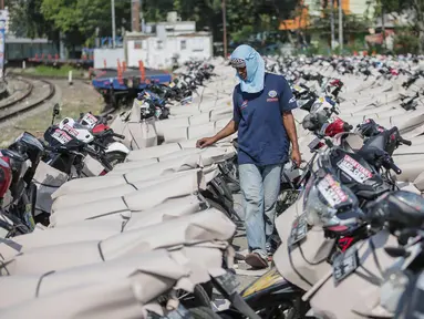 Pekerja melewati motor pemudik sebelum dikirim dengan kereta api di Stasiun Jakarta Gudang, Selasa (28/5/2019). Direktorat Lalu Lintas dan Angkutan Kereta Api Kementerian Perhubungan mengangkut 18.096 motor pemudik secara gratis pada mudik Lebaran 2019. (Liputan6.com/Faizal Fanani)