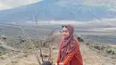 Berlibur di Bromo, Ria mengenakan cardigan panjang orange dipadukan dress kotak-kotak. Lalu Moana mengenakan atasan ungu dipadukan celana orange. [@riaricis1795]