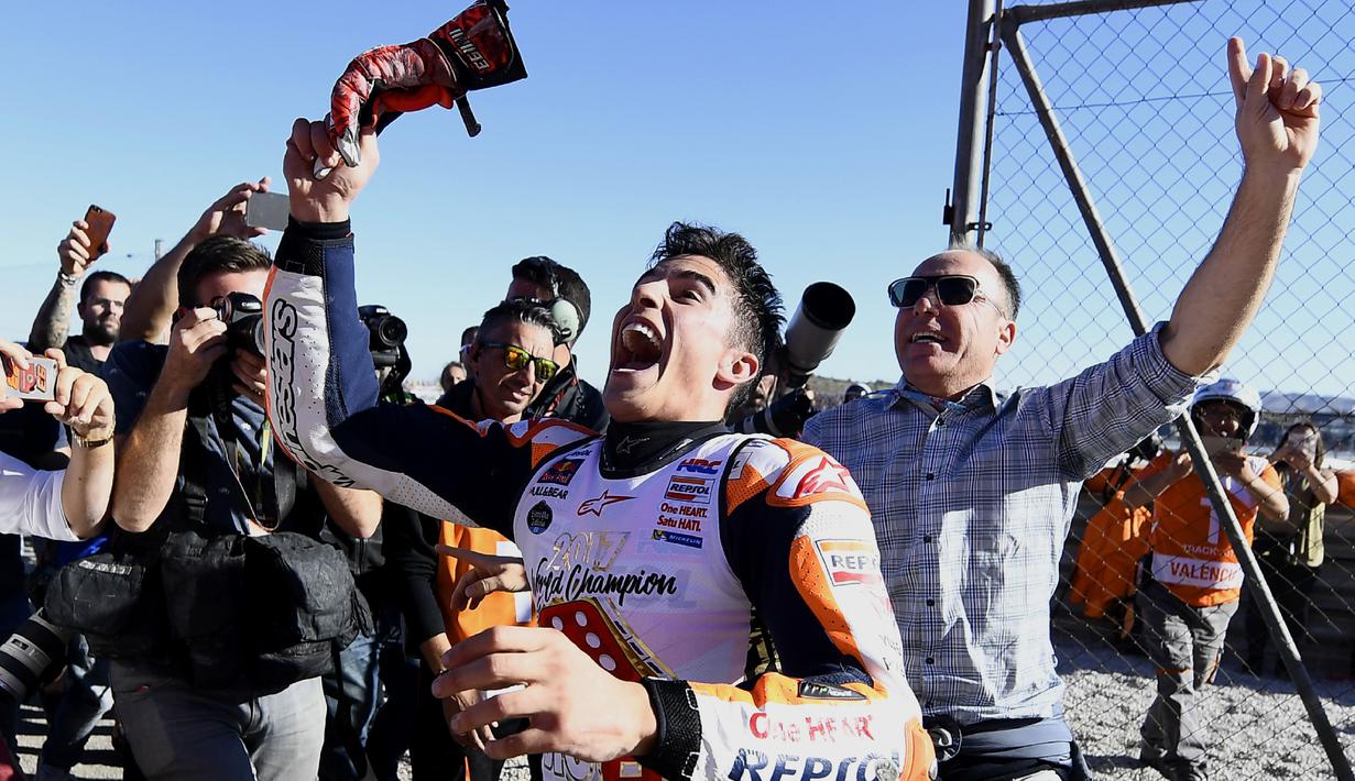 Marc Marquez melempar sarung tangan kepada fans usai mengunci gelar juara dunia MotoGP 2017 pada balapan MotoGP Valencia di Ricardo Tormo Circuit, Cheste, (12/11/2017). Gelar tersebut merupakan yang keempat buat Marquez.  (AFP/Jose Jordan)