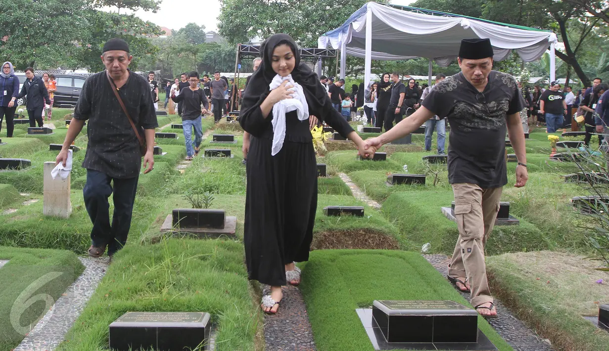 Penyanyi Ashanty dan Anang Hermansyah bergandengan tangan usai prosesi pemakaman sang ibunda, Ratu Farida, di TPU Jeruk Purut, Jakarta, Senin (7/11). Menurut kabar, ibunda Ashanty meninggal setelah jatuh dari kamar mandi. (Liputan6.com/Herman Zakharia)