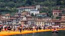 Sejumlah wisatawan berjalan di atas instalasi "The Floating Piers" karya Christo Vladimirov Javacheff di Danau Iseo, Italia, (24/6). Proyek seni instalasi ini telah menghabiskan biaya USD 16,7 juta atau sekitar Rp 224 miliar. (REUTERS/Stefano Rellandini)